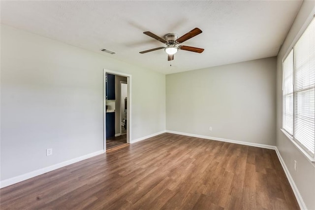 spare room with visible vents, ceiling fan, wood finished floors, and baseboards