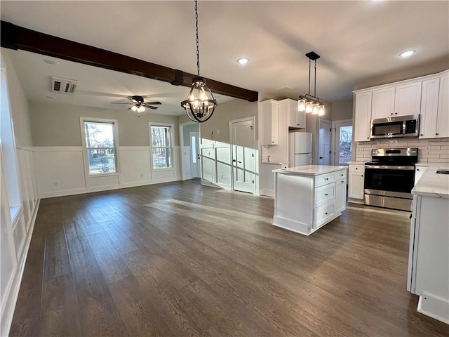 kitchen with visible vents, beam ceiling, dark wood finished floors, stainless steel appliances, and white cabinets