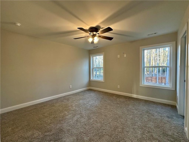 empty room featuring visible vents, a ceiling fan, baseboards, and dark colored carpet