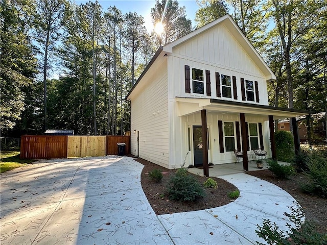 view of front facade featuring board and batten siding, covered porch, and fence