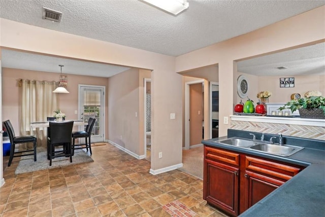 5865 El Segundo Way, Atlanta, GA 30349 - kitchen with dark countertops, a textured ceiling, hanging light fixtures, dark brown cabinets, and light stone finish flooring