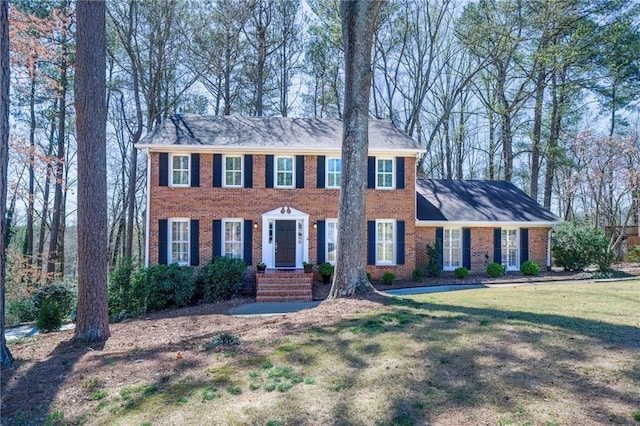 colonial home featuring brick siding and a front yard