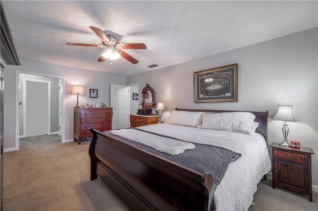 bedroom featuring light colored carpet, baseboards, a ceiling fan, and a textured ceiling