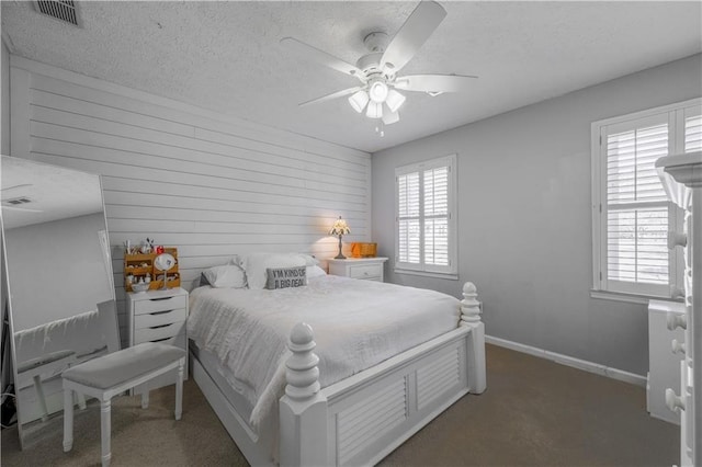 bedroom featuring multiple windows, carpet, baseboards, wood walls, and a textured ceiling