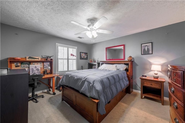 bedroom featuring light carpet, baseboards, a desk, ceiling fan, and a textured ceiling