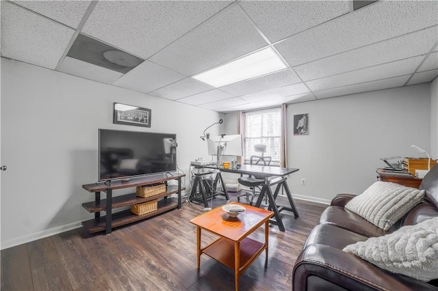 living area with baseboards, a paneled ceiling, and wood finished floors