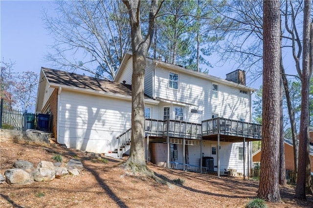 rear view of house featuring a deck, a chimney, stairway, and fence