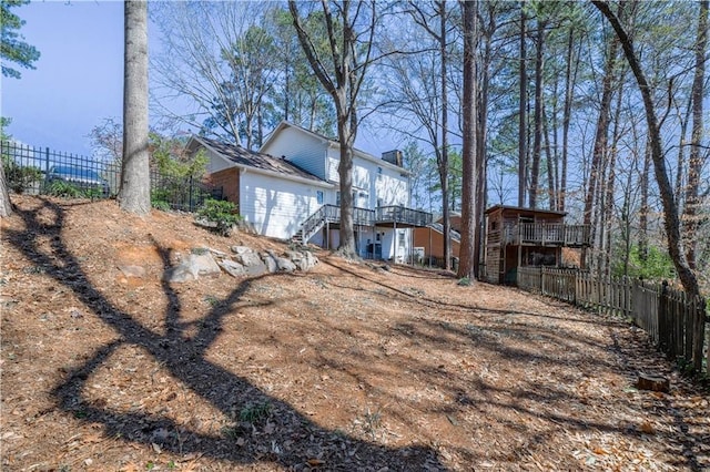 back of house featuring stairs, a chimney, a deck, and fence