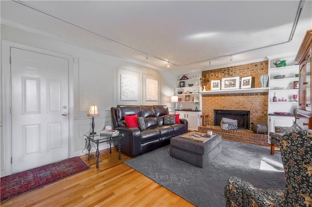 living area featuring wood finished floors, rail lighting, a fireplace, and built in features