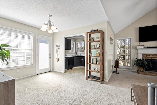 interior space with light carpet, a fireplace, lofted ceiling, and an inviting chandelier