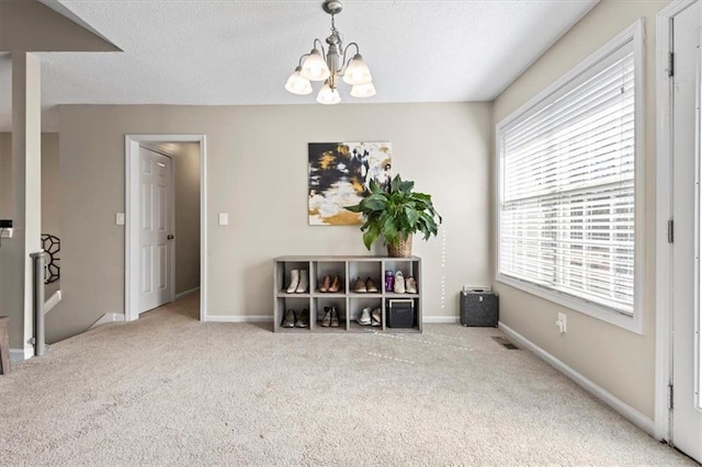 interior space featuring carpet, a textured ceiling, baseboards, and an inviting chandelier