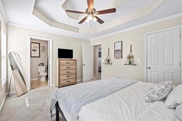 bedroom featuring light carpet, baseboards, ceiling fan, ornamental molding, and a tray ceiling