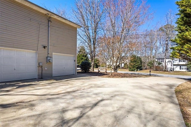 view of property exterior featuring a garage and concrete driveway