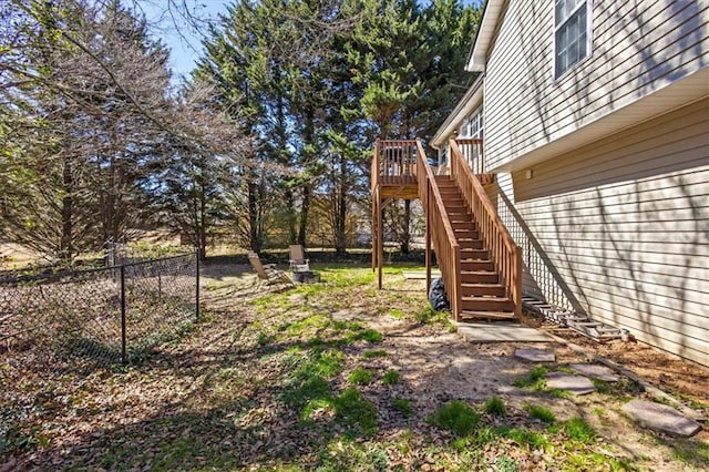 view of yard featuring fence, a wooden deck, and stairs