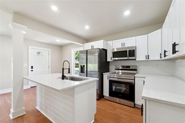 2081 Verbena St NW, Atlanta, GA 30314 - kitchen with stainless steel appliances, tasteful backsplash, light wood finished floors, a center island with sink, and white cabinets