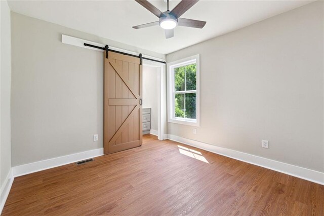 2081 Verbena St NW, Atlanta, GA 30314 - unfurnished bedroom featuring light wood-style floors, a barn door, and a ceiling fan