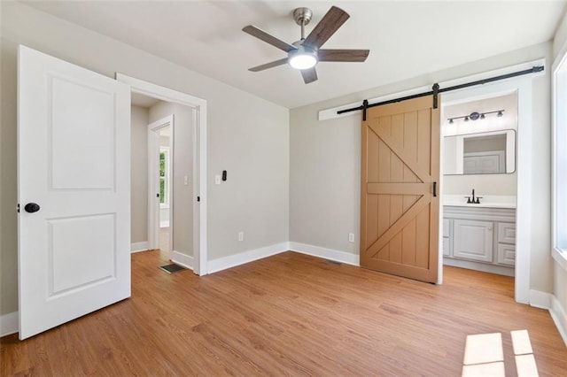 2081 Verbena St NW, Atlanta, GA 30314 - unfurnished bedroom featuring light wood-style flooring, a barn door, connected bathroom, and ceiling fan