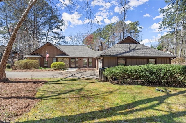 view of front of house with an attached garage, a shingled roof, driveway, and a front lawn