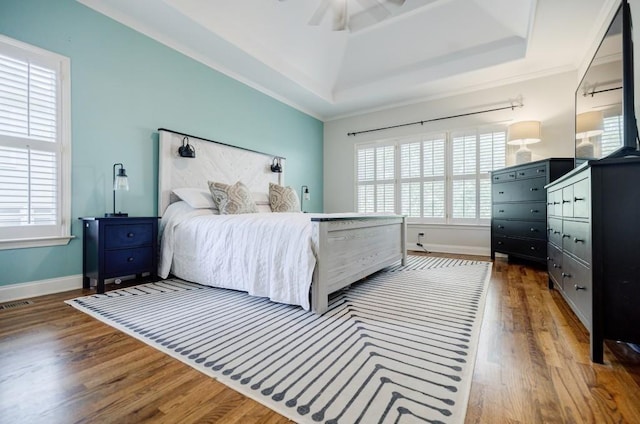 bedroom with a raised ceiling and wood-type flooring