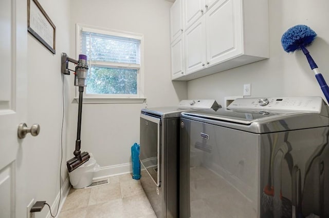 washroom featuring cabinets, light tile patterned floors, and washing machine and clothes dryer