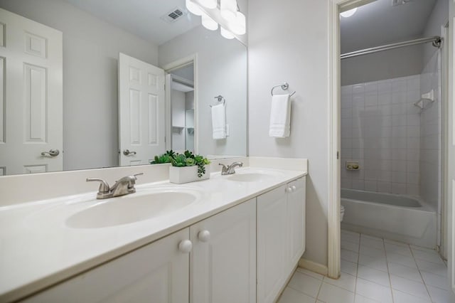 full bathroom with tile patterned flooring, tiled shower / bath, vanity, and toilet