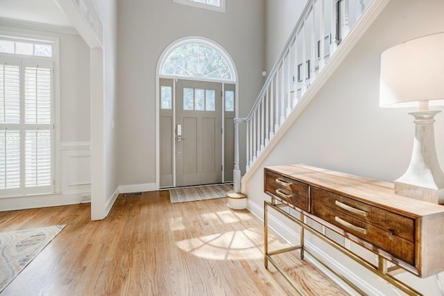 foyer entrance with a towering ceiling and light hardwood / wood-style floors