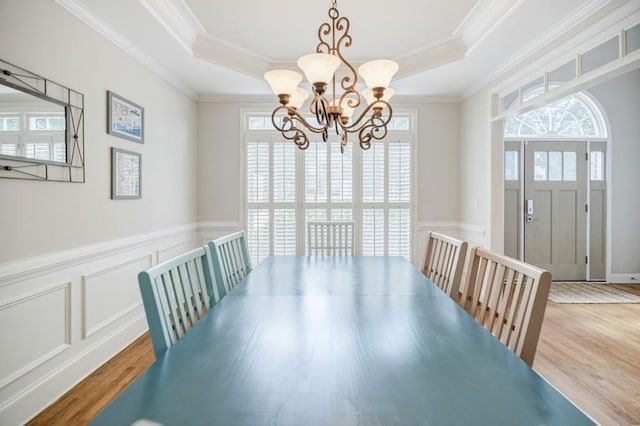 dining area featuring ornamental molding, a raised ceiling, and light hardwood / wood-style flooring