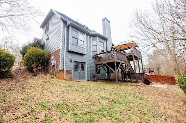 back of property featuring a wooden deck and a lawn