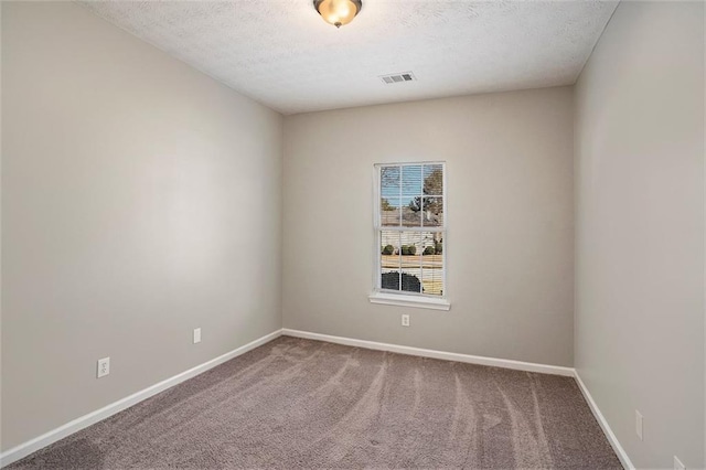 carpeted spare room with visible vents, baseboards, and a textured ceiling