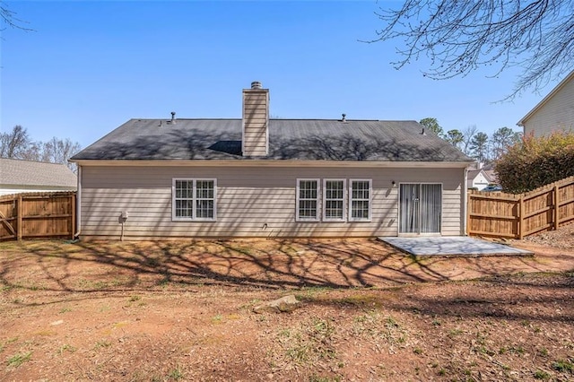 rear view of house featuring a patio area, a chimney, and a fenced backyard