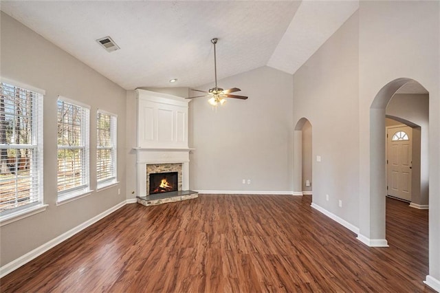 unfurnished living room with visible vents, baseboards, arched walkways, and dark wood finished floors