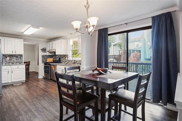 dining space with a textured ceiling, dark wood-type flooring, sink, and a chandelier