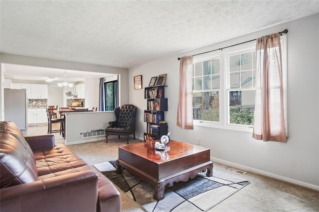 carpeted living room featuring a textured ceiling, a wealth of natural light, and an inviting chandelier