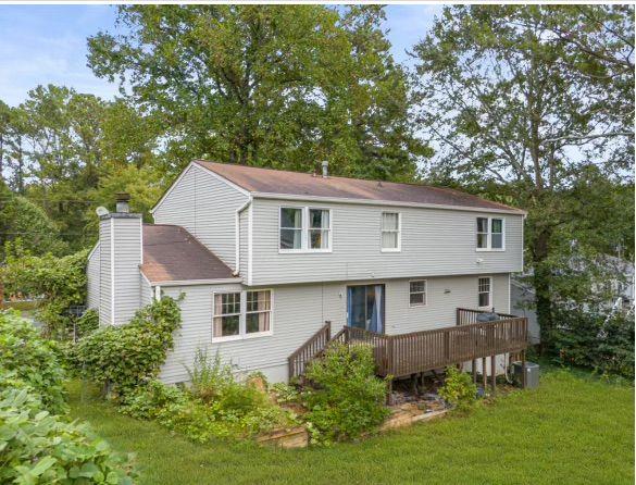 rear view of house featuring a lawn and a deck