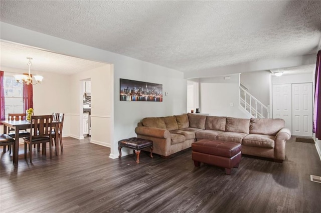 living room featuring a textured ceiling, dark wood-type flooring, and a notable chandelier