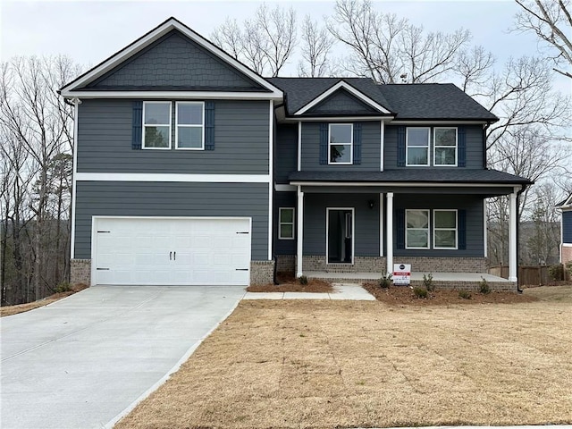 view of front of house featuring brick siding, a garage, a front yard, concrete driveway, and covered porch