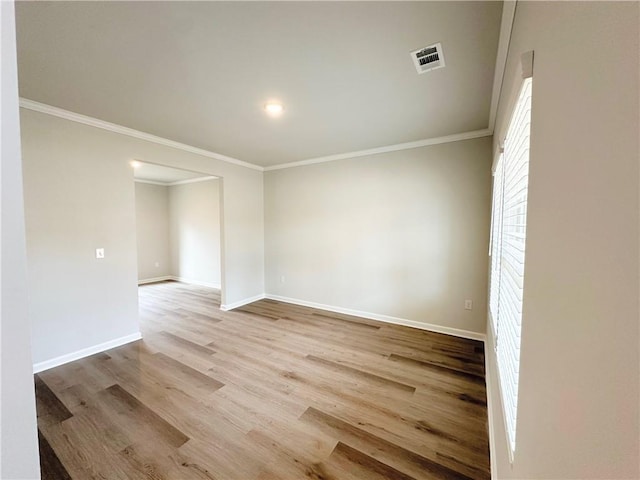 empty room featuring visible vents, baseboards, crown molding, and wood finished floors