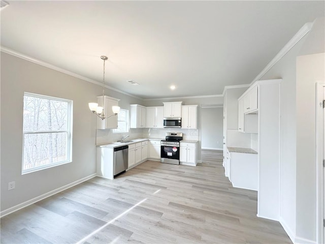 kitchen with a sink, appliances with stainless steel finishes, crown molding, and a chandelier
