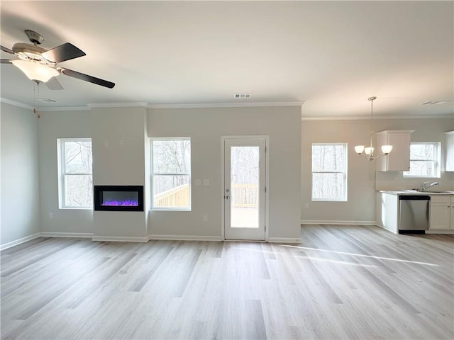 unfurnished living room with crown molding, a glass covered fireplace, light wood finished floors, and visible vents