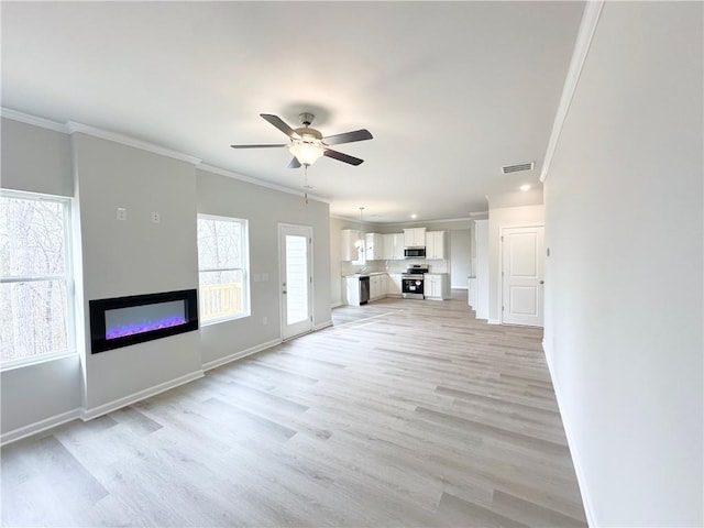 unfurnished living room with ceiling fan, a glass covered fireplace, ornamental molding, and light wood-style flooring