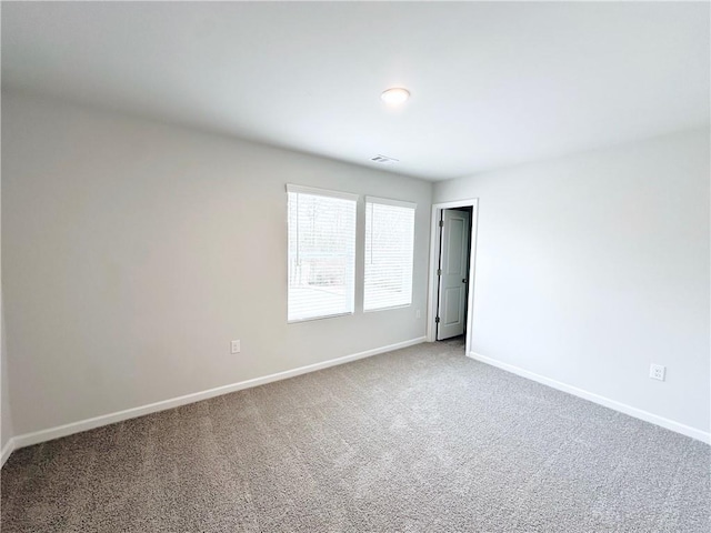 carpeted spare room featuring baseboards and visible vents