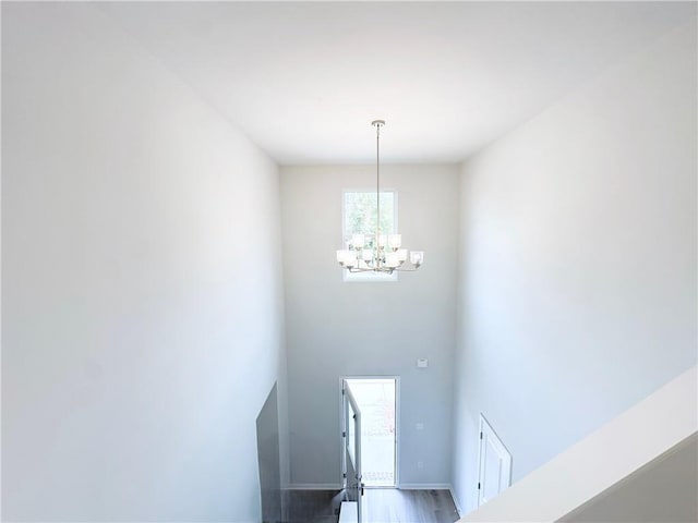 foyer entrance with baseboards, wood finished floors, and a notable chandelier