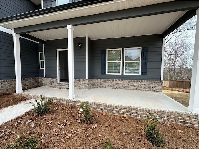 view of exterior entry featuring a porch and brick siding