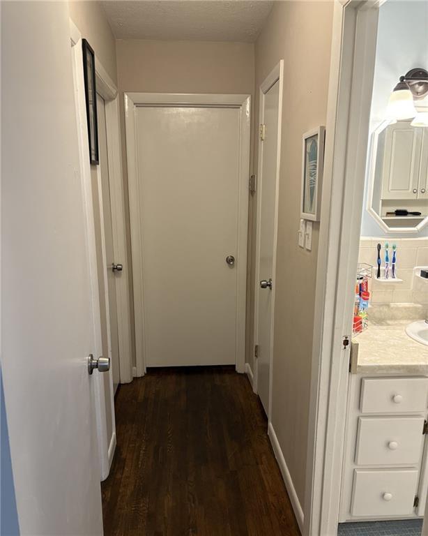 kitchen featuring dark wood-type flooring, white appliances, sink, and a textured ceiling