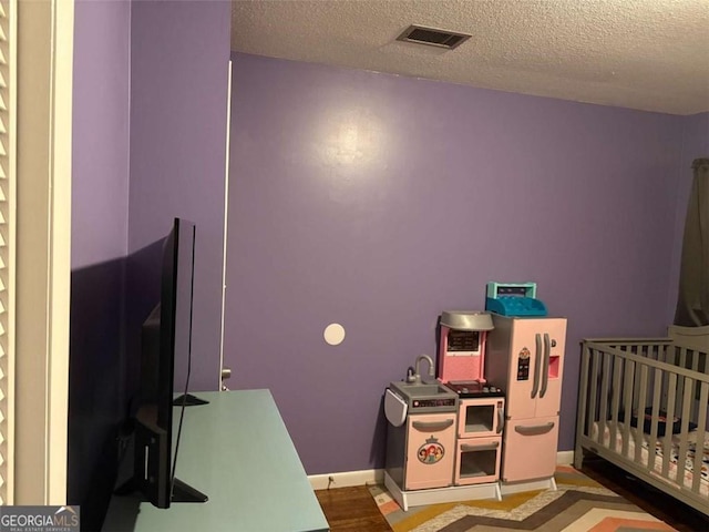 bedroom with a crib and a textured ceiling