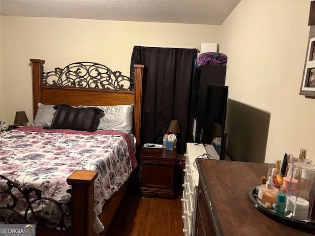 bedroom with dark hardwood / wood-style floors and a textured ceiling