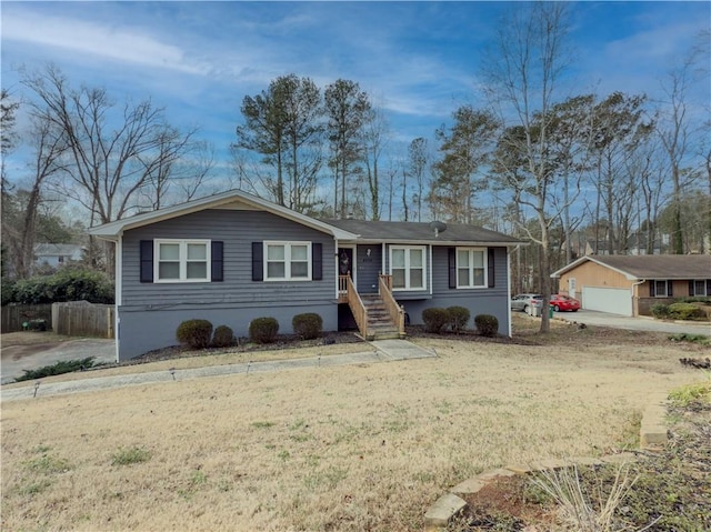 ranch-style house featuring a garage, fence, and a front lawn