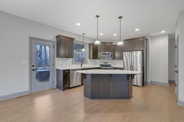 kitchen featuring a breakfast bar, stainless steel appliances, sink, a kitchen island, and hanging light fixtures