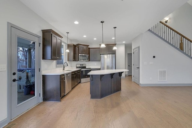 kitchen with sink, a center island, a kitchen breakfast bar, pendant lighting, and appliances with stainless steel finishes