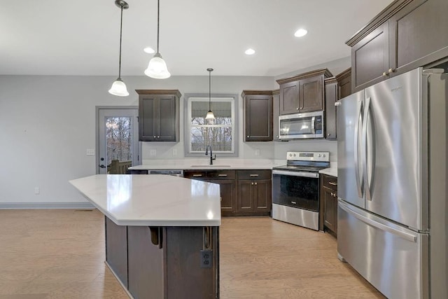 kitchen with stainless steel appliances, a kitchen island, hanging light fixtures, and sink